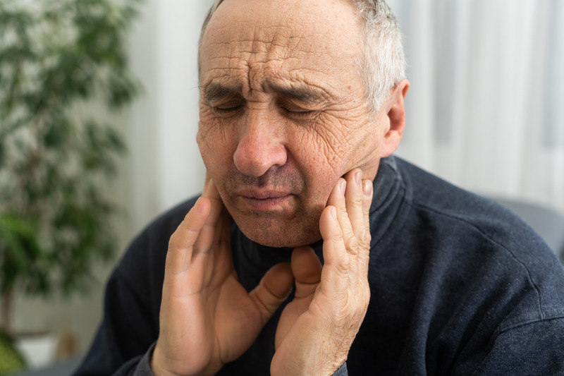 Patient holding their cheek due to a denture sore